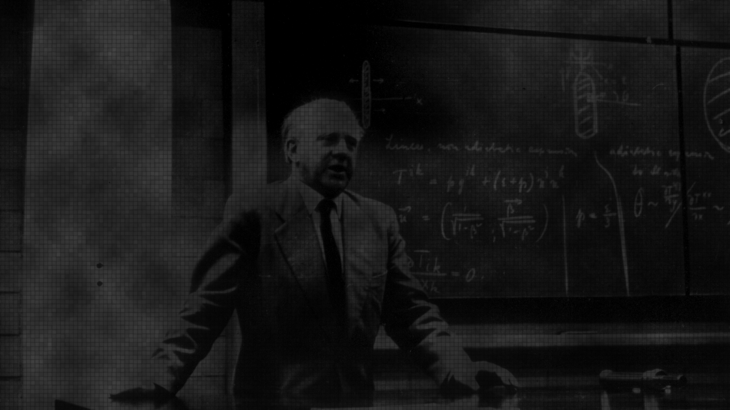 Werner Heisenberg lecturing in front of a blackboard with mathmatical equations.